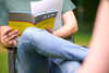Mann sitzt mit verschränkten Beinen auf einem Stuhl und hält ein Buch mit der Aufschrift AVR in der Hand