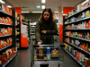 Frau im Supermarkt vor vollem Einkaufswagen